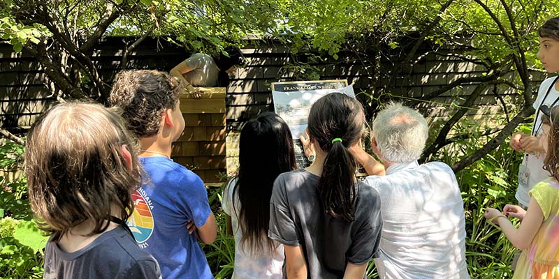 Campers examine a 1909 sketch with preservationist Doug Freerksen and carpenter Kady Creager to uncover a section of the original Home and Studio fence hidden within today’s wall.