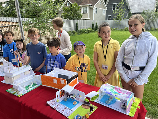 3rd – 5th grade campers stand proudly by their models during the Friday Showcase, where friends and family view their camper’s hard work.